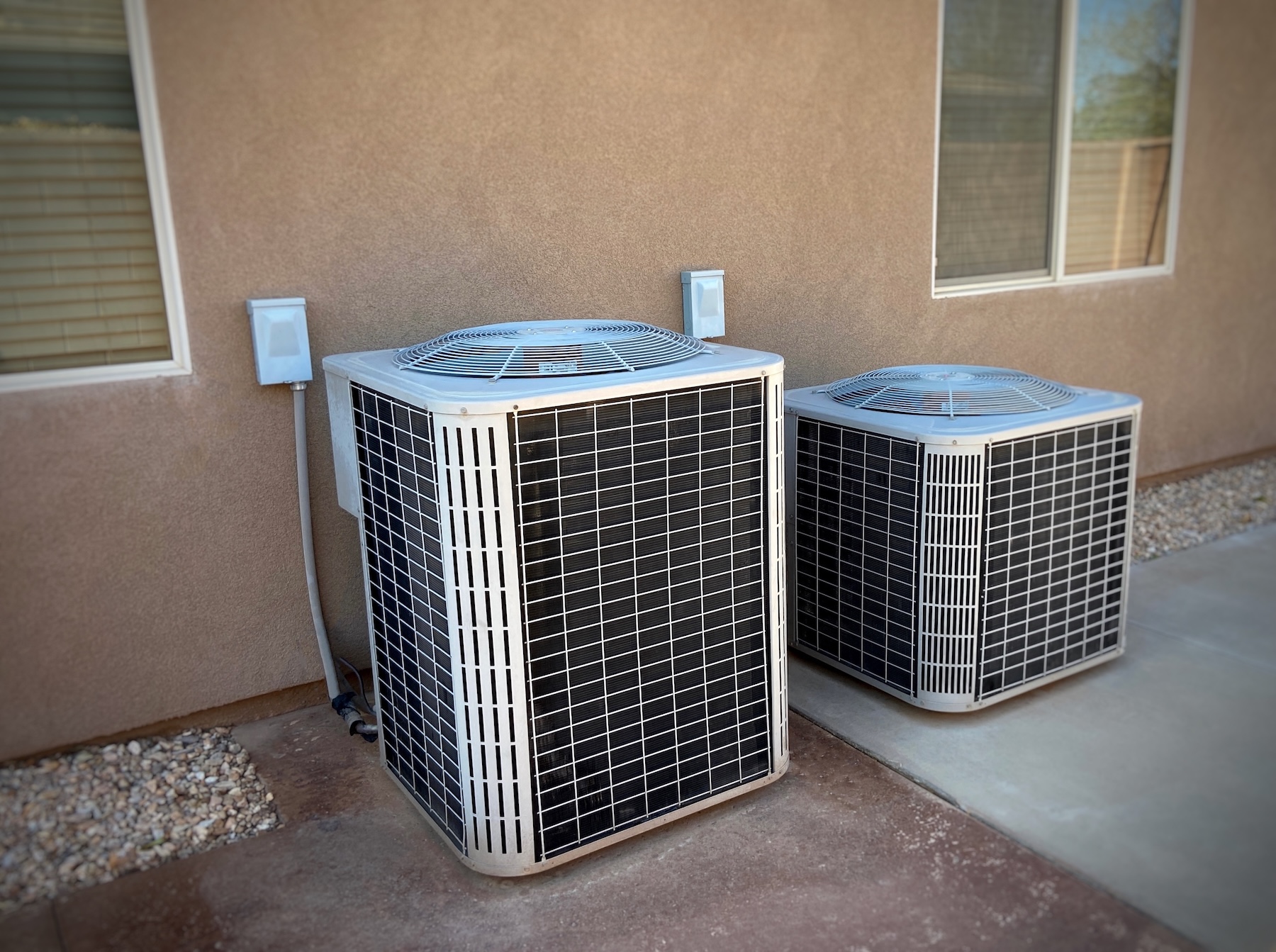 Double AC units on side of home with dryscape on driveway
