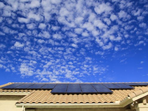 partly cloudy day over a house with rooftop solar panels