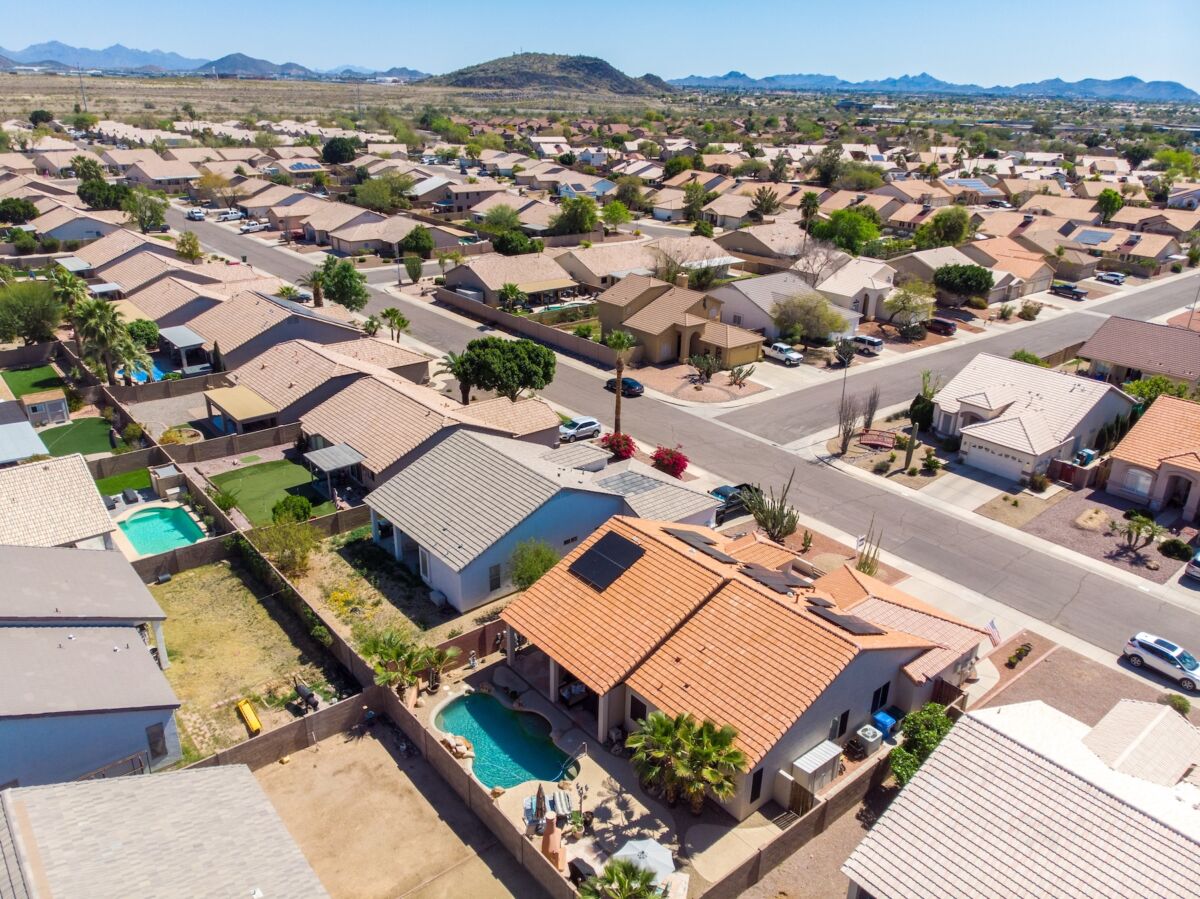 An aerial view of an Arizona neighborhood with a home that has solar panels and a pool in the foreground of the image