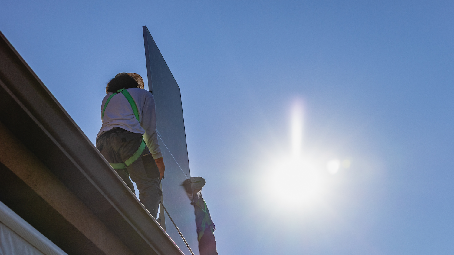 Two solar installers atop a roof in Arizona