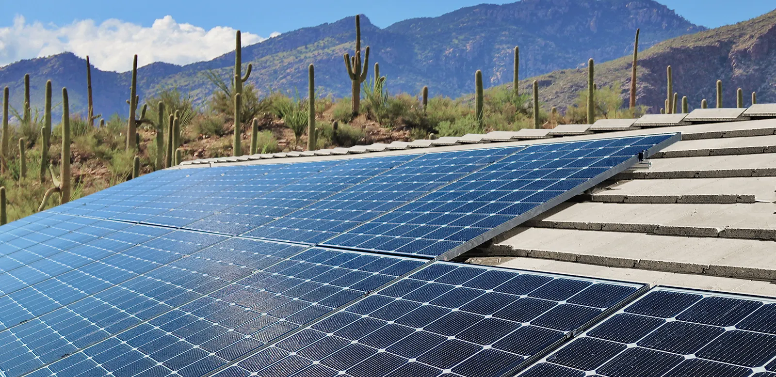 Clean solar panels on an Arizona tile roof with desert mountains and saguaro cacti in the background